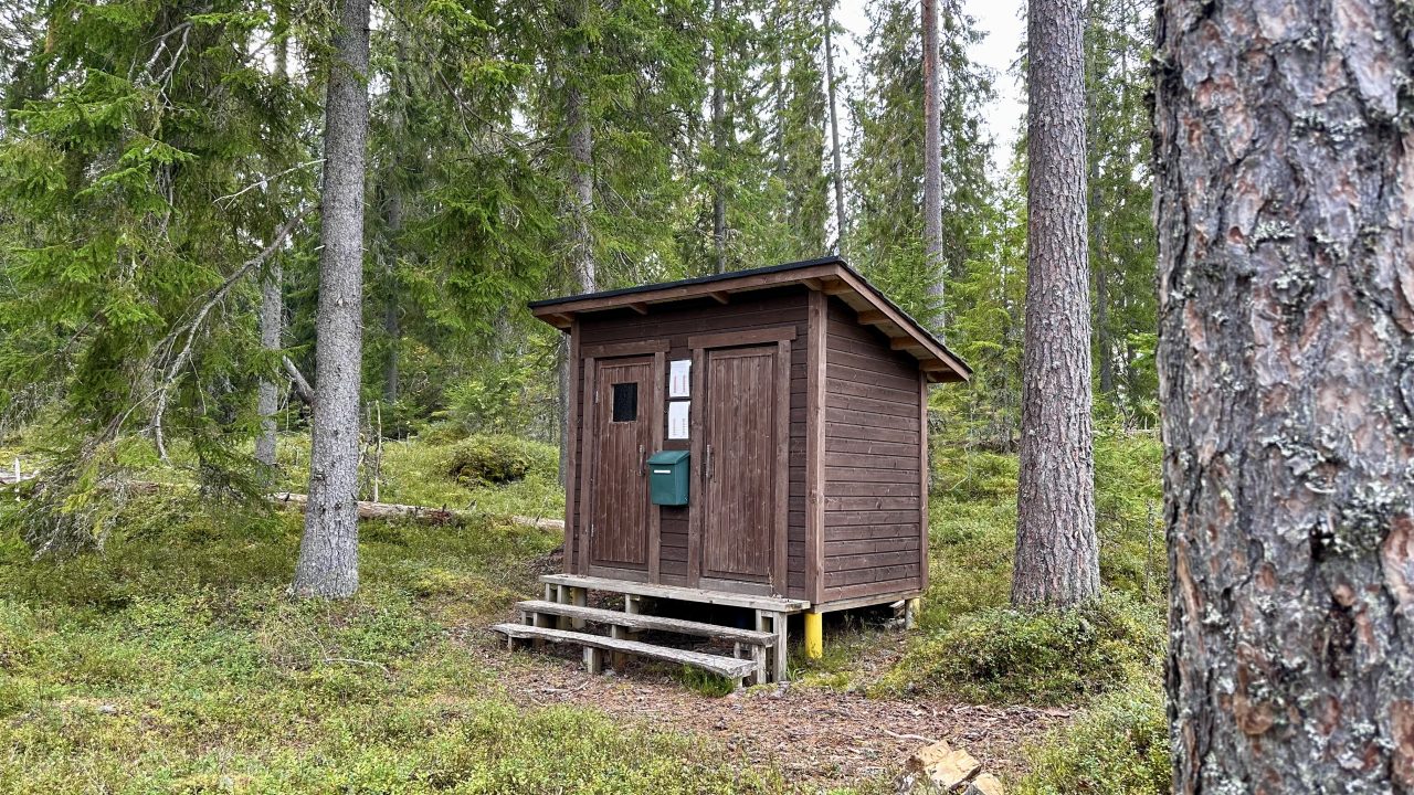 Kaksiovinen puinen pieni rakennus, johon johtaa kolme porrasta.