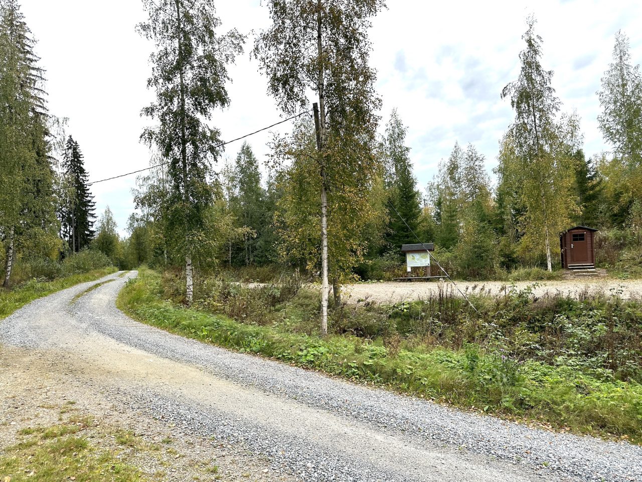 Metsätien vieressä on hiekkakenttä, jonka reunalla infokyltti ja kuivakäymälä.