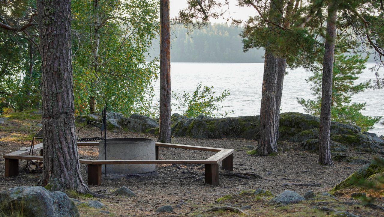 Metsäisellä kalliolla on betonirengas, jonka ympärillä on puiset penkit.
