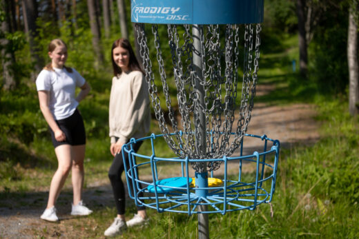 Kaksi nuorta pelaavat frisbeegolfia Hauholla.