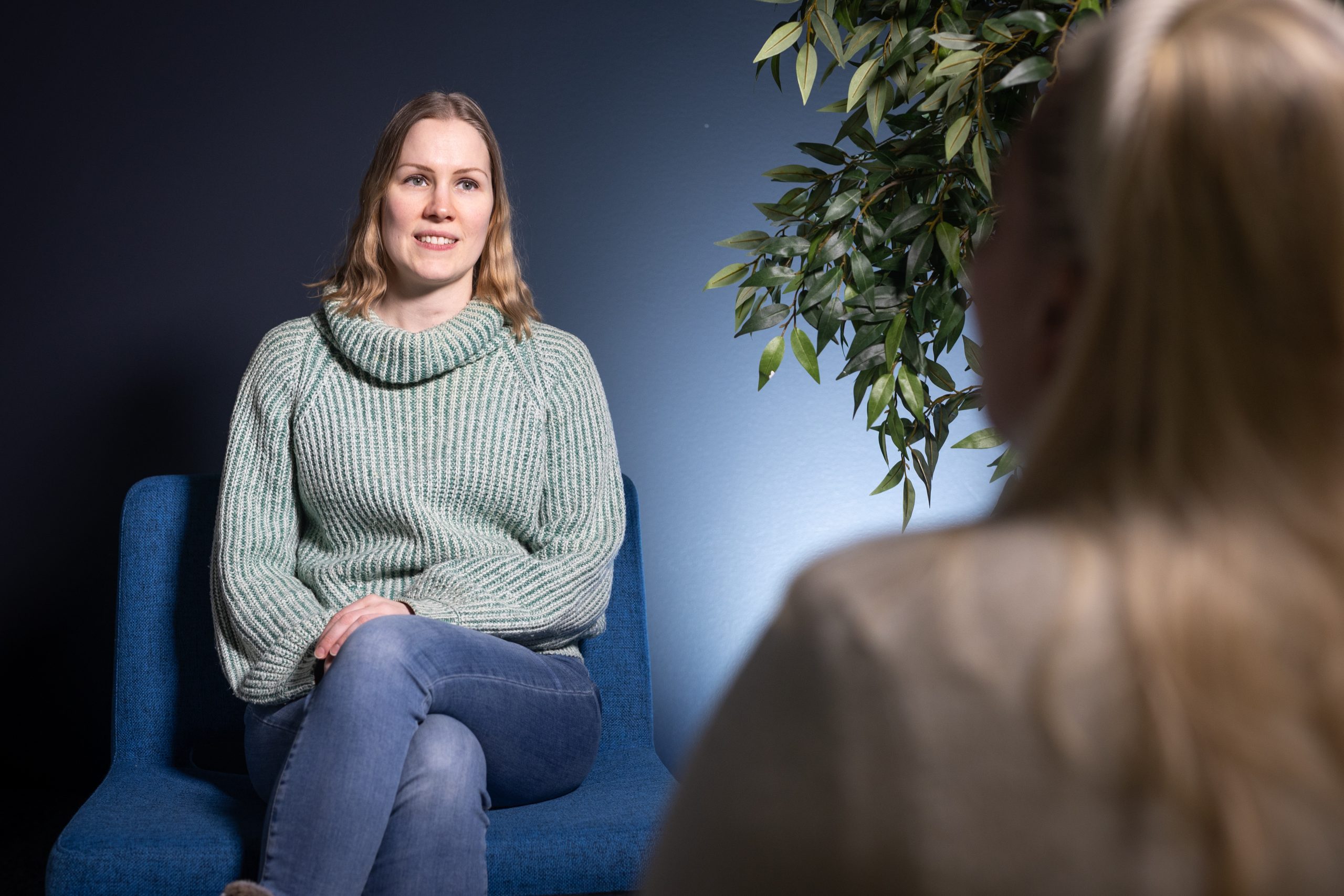 Henkilö istuu tuolissa ja keskustelee toisen henkilön kanssa.