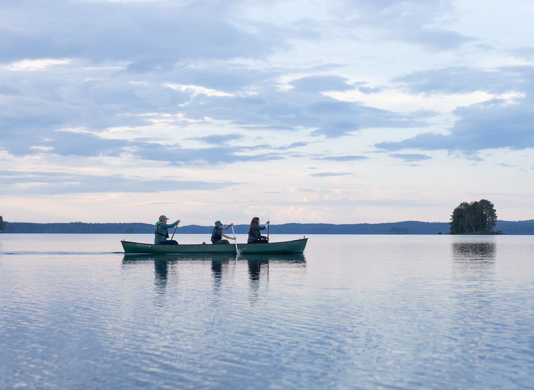 Kolme ulkoilijaa melovat järvellä.