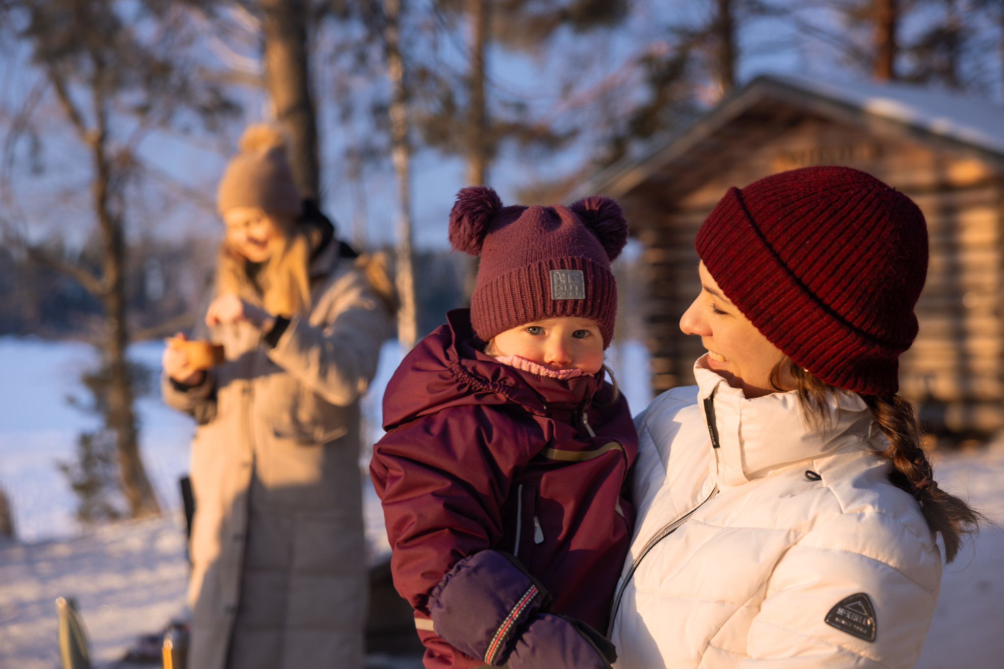 Lapsi ja kaksi aikuista Tervaniemen nuotiopaikalla talvella.