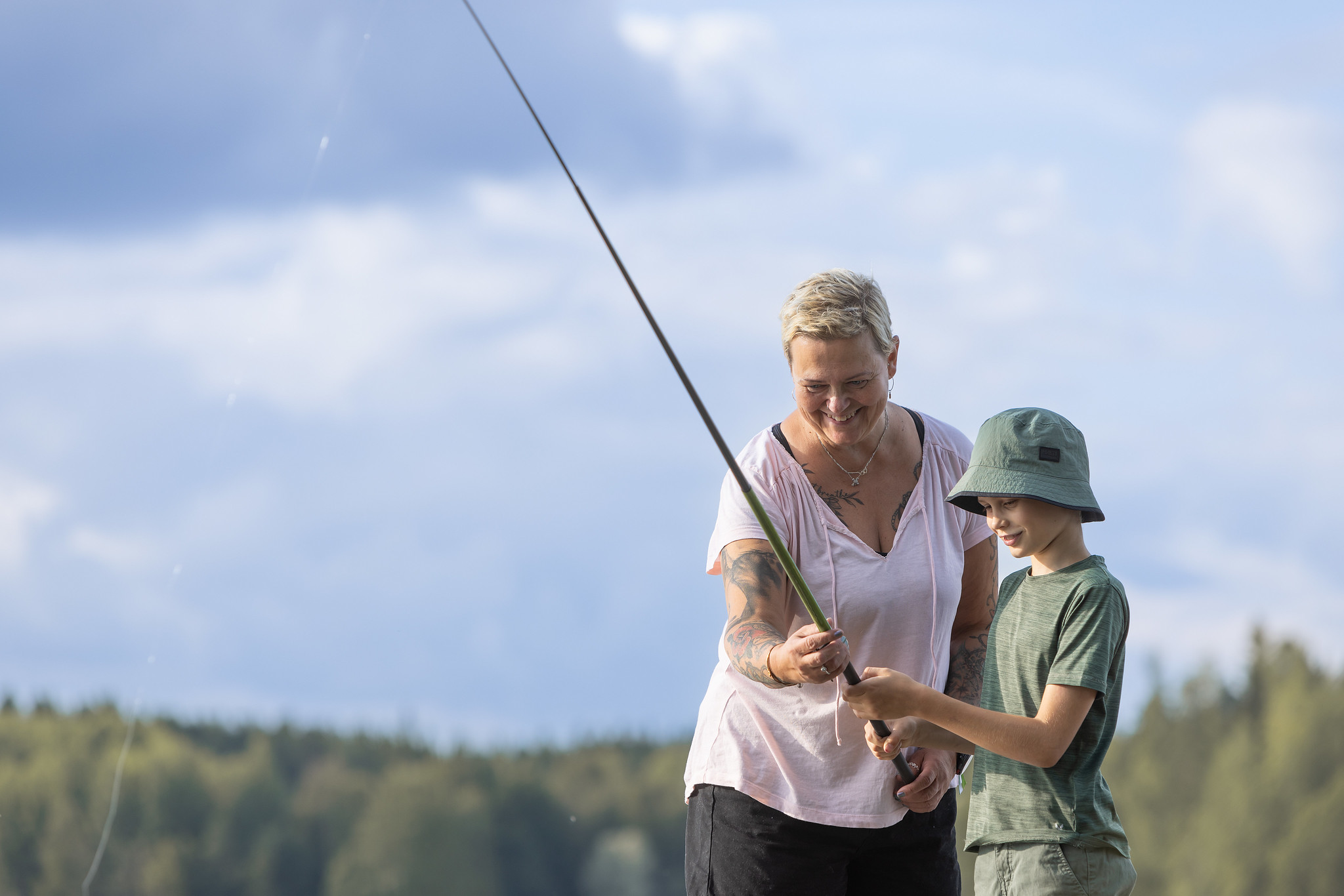 Lapsi kalastaa aikuisen kanssa.