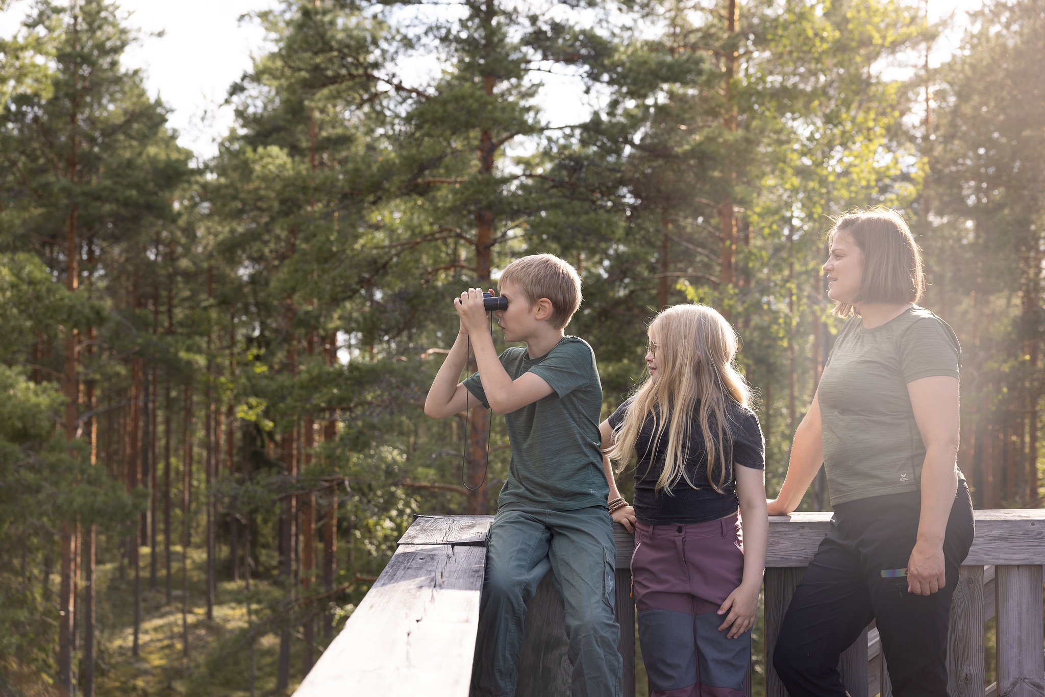 Lapsi kiikaroi metsässä perheensä kanssa.