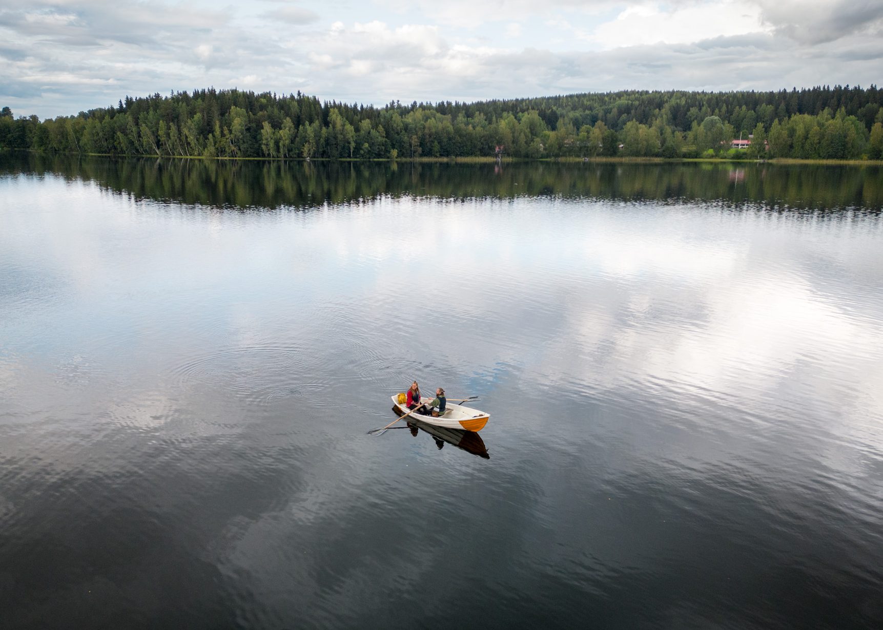 Ilmakuva kahdesta soutajasta, jotka soutavat kaupunkiveneellä.