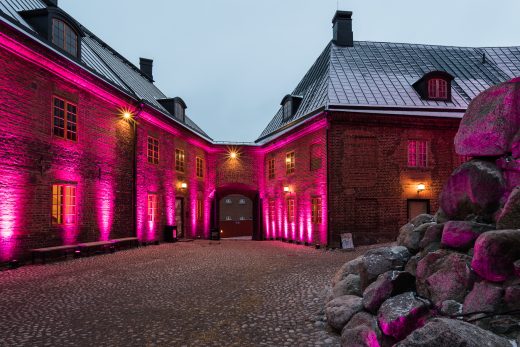 Linnan sisäpiha kirkkailla punaisilla valoilla. Kuvan perällä kaareva ovi.