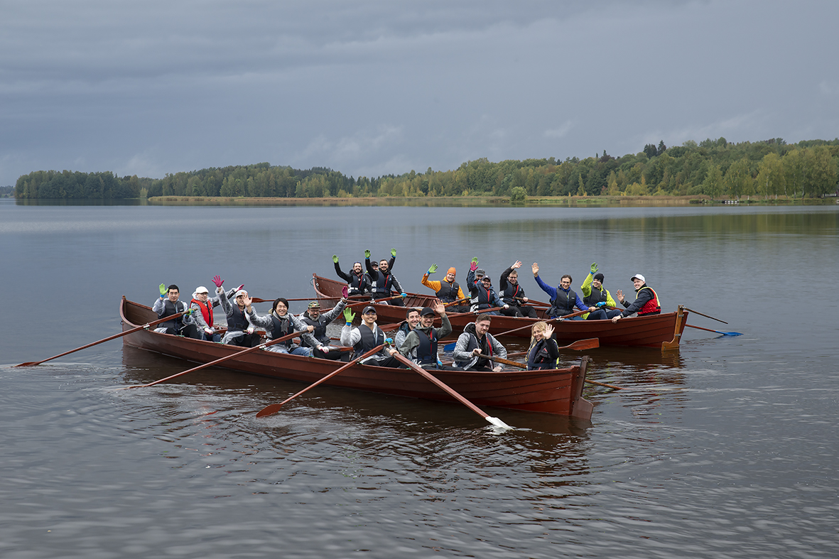 Kirkkoveneet Vanajavedellä täynnä ihmisiä joilla kädet ilmassa.