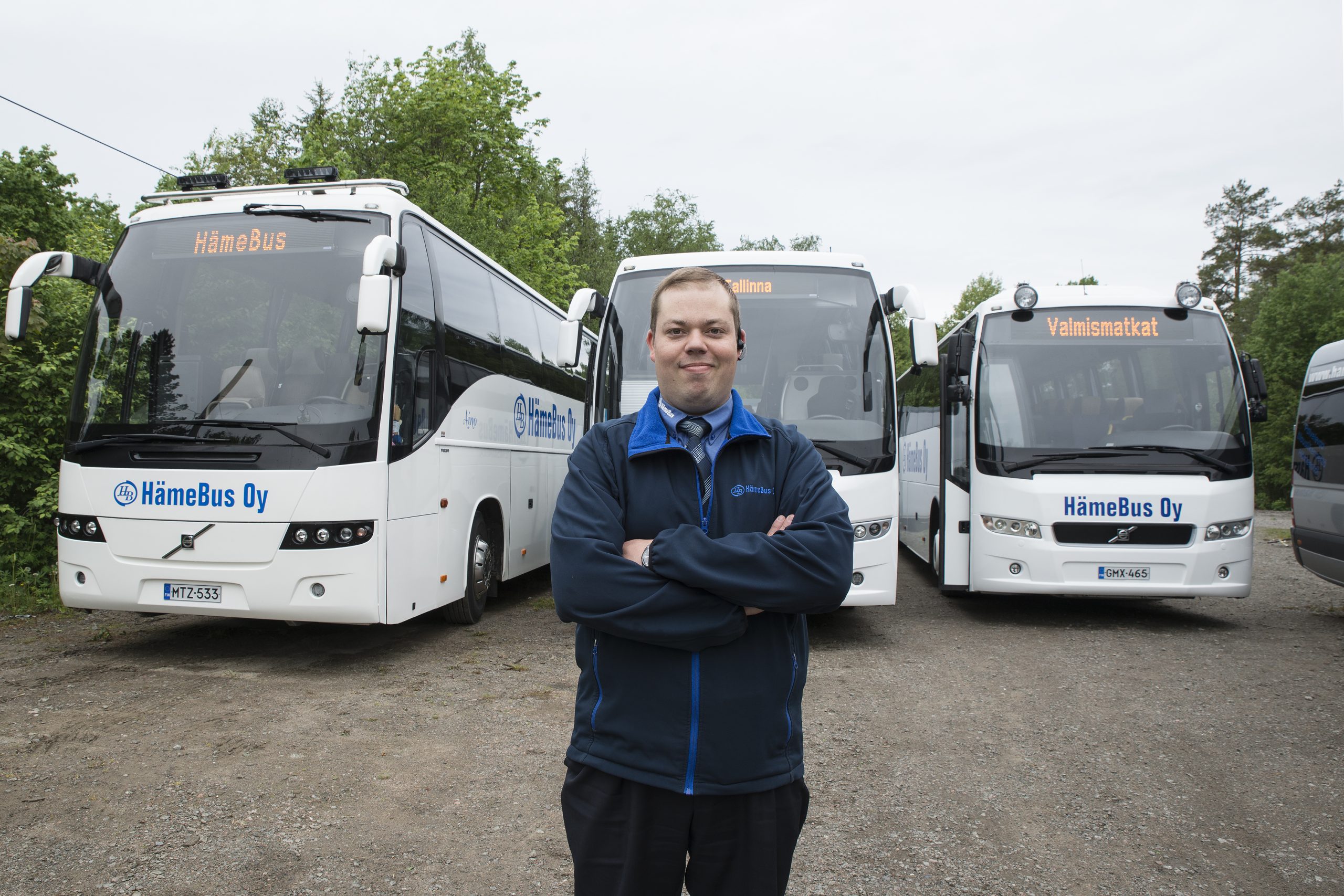 Linja-auton kuljettaja seisoo valkoisten bussin edessä.