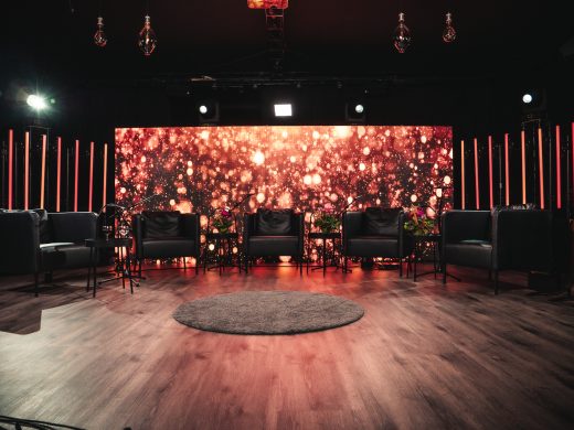 Studio jossa rivissä tuoleja ja punainen värikäs valaistu tausta.