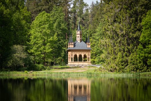 Ruusulaakson paviljongin rakennus puiden ympäröimänä veden äärellä.