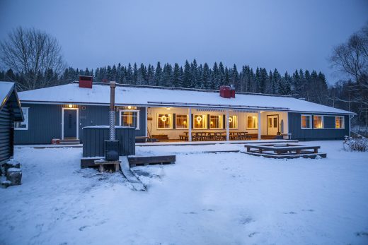 Talvinen sininen hetki jossa pitkä sininen rakennus isoilla ikkunoilla joista tulee valoa.