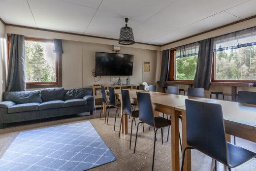 Oleskelutilaa baarijakkaroilla ja sohvilla. Takaseinällä televisio.