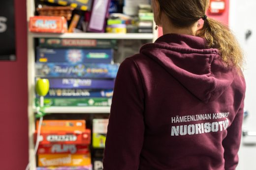 Nuorisotyöntekijä lautapelihyllyn edessä nuorisotilalla.
