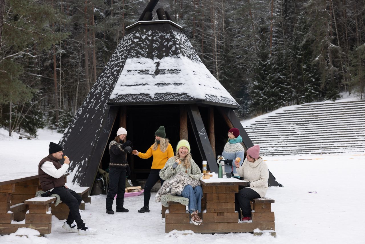 Joukko ihmisiä kodalla. Luminen ja talvinen maisema.