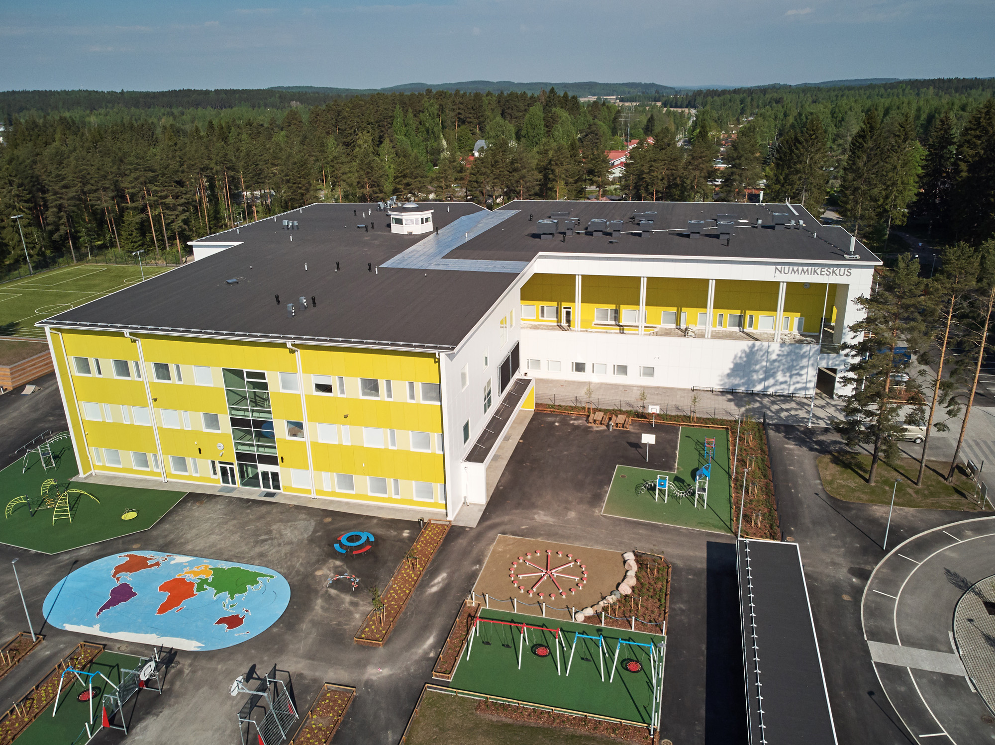 Iso kelta-valkoinen rakennus ja piha-aluetta.