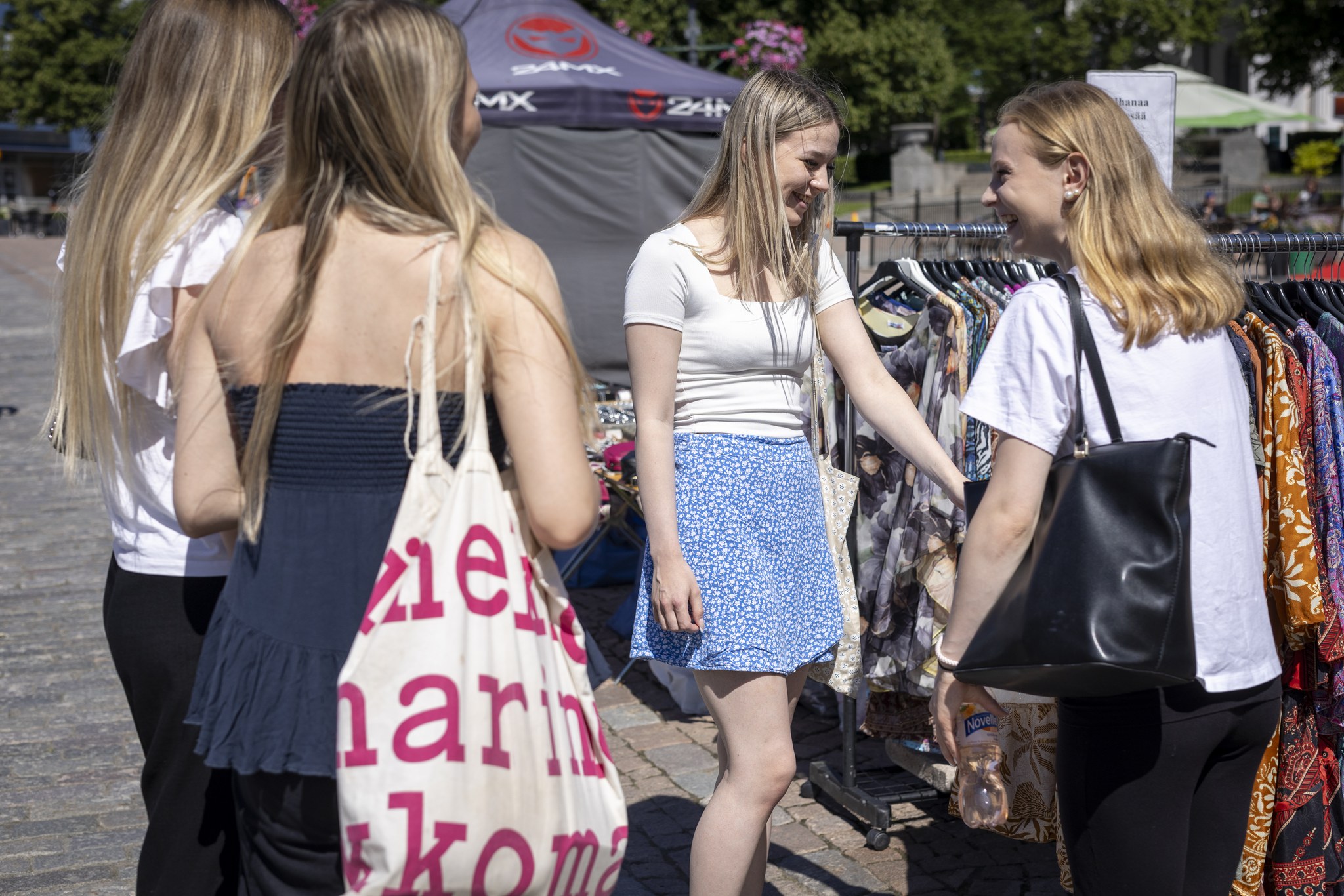 Neljä nuorta naista kiertelee torikojuja Hämeenlinnan torilla