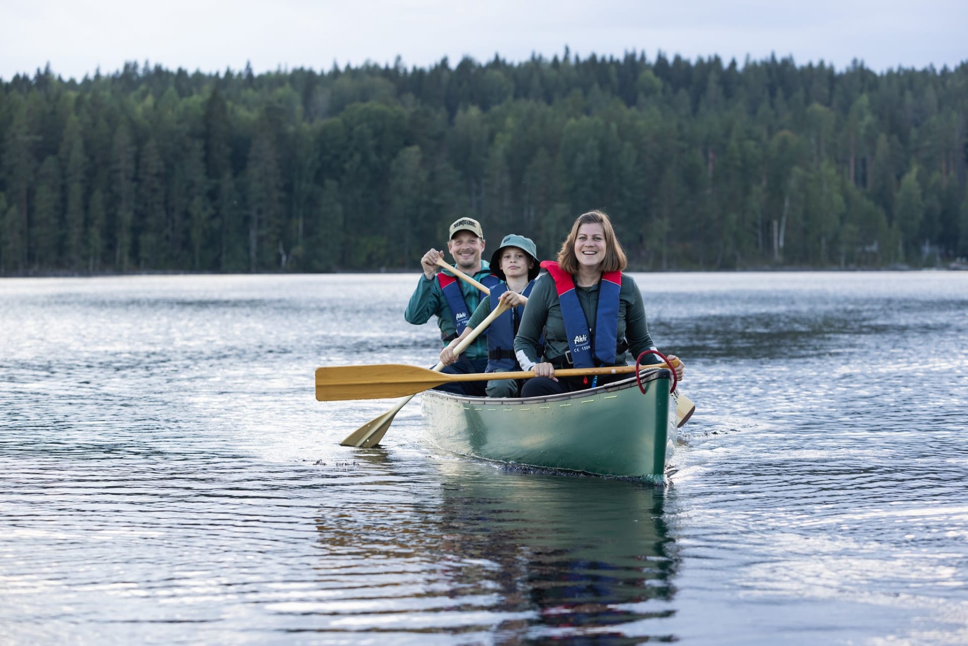 3 persons sitting in a canoe and smiling