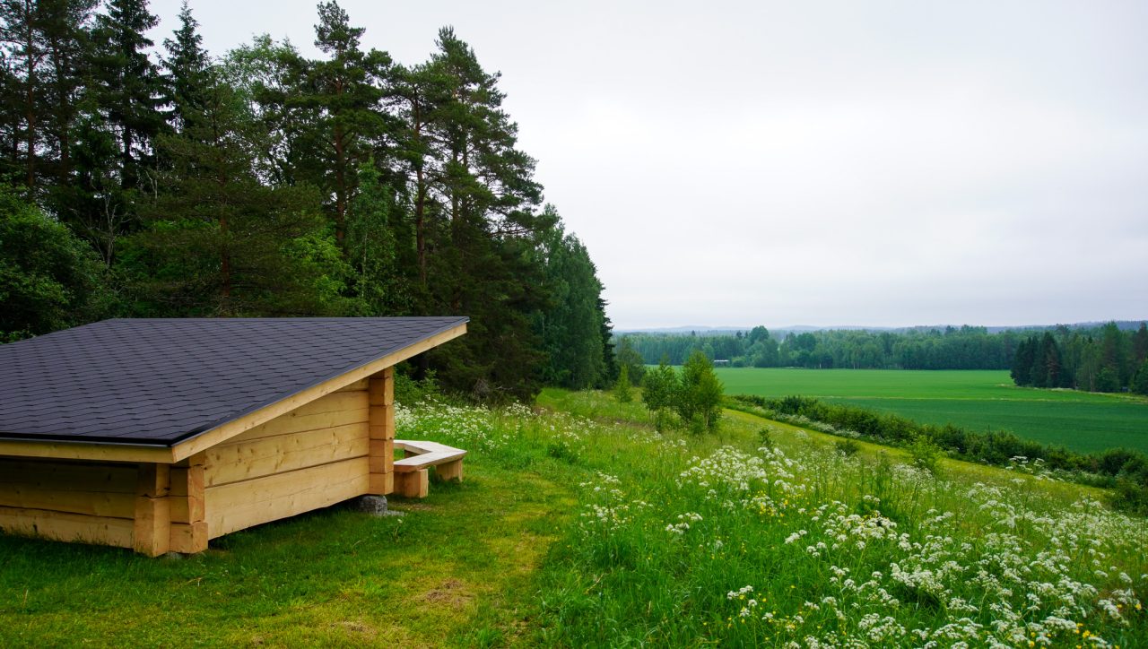 The shelter is at the top of the hill, and there is a field in front of it.